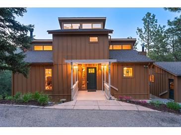 Charming home featuring covered entryway with decorative columns, dark green front door, and manicured landscaping at 207 Kelly E Rd, Boulder, CO 80302