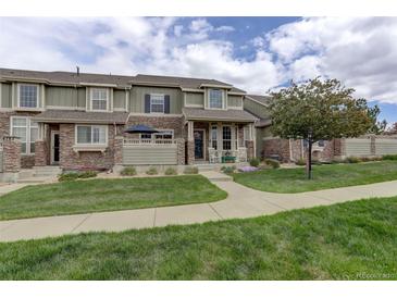 Charming townhome with stone accents, a well-manicured lawn, and a welcoming front porch with rocking chairs at 4784 Raven Run, Broomfield, CO 80023