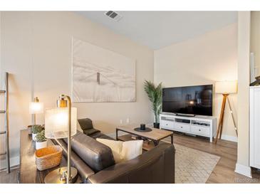 Living room with comfortable leather seating, a decorative rug, and a big screen TV at 5677 S Park Pl # C208, Englewood, CO 80111