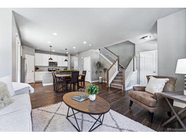 Open-concept living room features hardwood floors, modern furniture, a staircase, and an eat-in kitchen at 6771 Canosa St, Denver, CO 80221