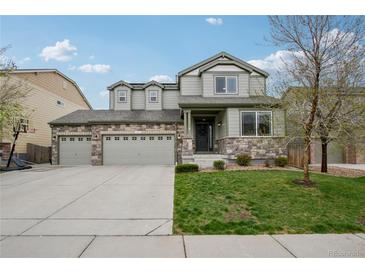 Charming two-story home featuring stone accents, a three-car garage, and a well-manicured lawn at 60 Stewart Way, Erie, CO 80516