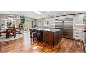Bright eat-in kitchen with stainless steel appliances, large island, and sliding doors to the outdoors at 10858 E Harvard Dr, Aurora, CO 80014