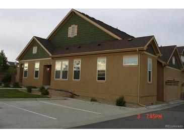 Tan home with green trim, showing a two-car garage and partial driveway at 12317 W Gould Ave, Littleton, CO 80127