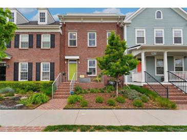Brick townhome featuring a vibrant green door and landscaped front yard at 8851 E 33Rd Ave, Denver, CO 80238
