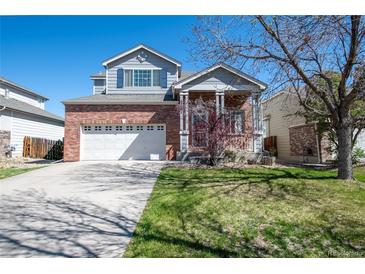 Charming two-story home featuring a well-maintained front yard, brick accents, and a two-car garage on a sunny day at 13931 E 104Th Dr, Commerce City, CO 80022