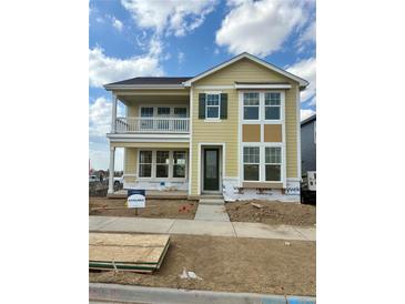 Charming two-story home featuring a covered porch, green door, many windows, and unfinished front yard at 24207 E 53Rd Dr, Aurora, CO 80019