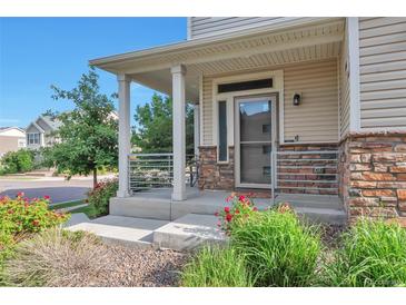 Charming covered front porch with stone accents and manicured landscaping provides great curb appeal at 18096 E 104Th Way, Commerce City, CO 80022