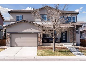 Charming two-story home featuring a two-car garage, covered porch with stone accents, and well-manicured lawn at 11025 Watermark St, Parker, CO 80134