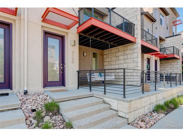 Inviting home exterior with a charming front porch swing, brick facade, and stylish purple door at 9180 E 52Nd Dr, Denver, CO 80238