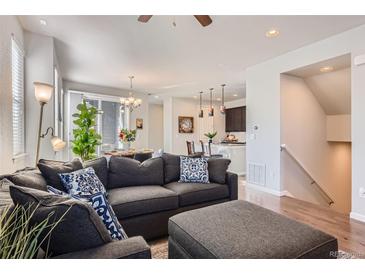 Comfortable living room features a large sectional sofa, wood floors, and a view into the dining area and kitchen at 7203 W Pacific Ave, Lakewood, CO 80227