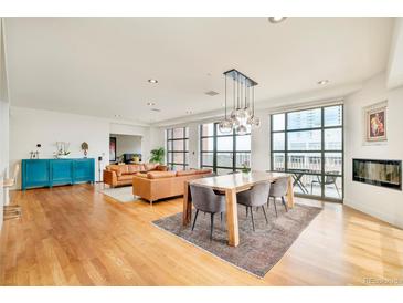 Open-concept living room and dining area with city views, hardwood floors, and fireplace at 1590 Little Raven St # 702, Denver, CO 80202