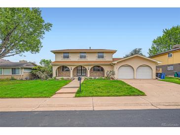Inviting two-story home with a charming facade, arched entryway, lush lawn, and a two-car garage at 7700 E Oxford Ave, Denver, CO 80237