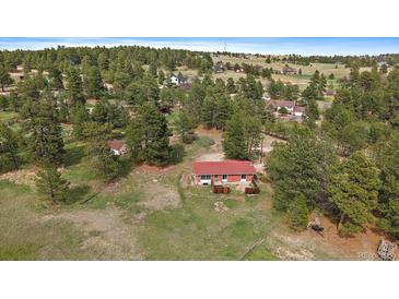 Aerial view of a charming red roofed home nestled among trees in a serene, rural setting at 3337 Ponderosa Rd, Franktown, CO 80116