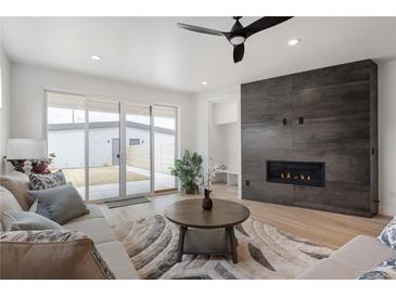 Bright living room features a modern fireplace, ceiling fan, and sliding doors to the backyard at 1953 W 47Th Ave, Denver, CO 80211