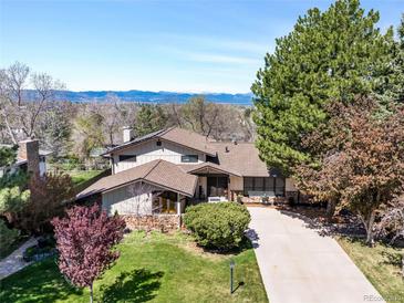 Expansive exterior with lush lawn, mature trees and mountain views on a sunny day at 6389 S Monaco Ct, Centennial, CO 80111