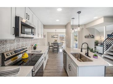 Bright kitchen boasts white cabinets, quartz counters, stainless appliances, and stylish backsplash at 909 Reynolds Farm Ln # C2, Longmont, CO 80503