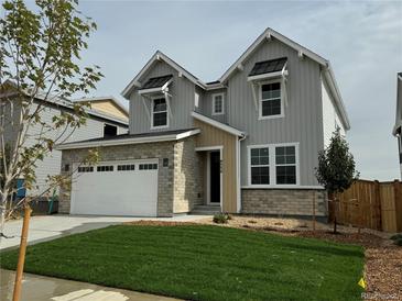 Charming two-story home showcasing a well-manicured lawn and a modern two-car garage at 9334 Quartz St, Arvada, CO 80007