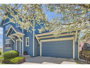 Charming blue two-story home with an attached garage and beautiful flowering trees in the front yard at 3752 Red Deer Trl, Broomfield, CO 80020