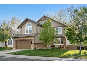 Charming two-story home with a well-manicured lawn, mature tree, and an attached two-car garage at 5997 S Yakima St, Aurora, CO 80015