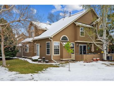 Charming two-story home features a side yard with mature trees and partial snow cover in a cozy neighborhood at 10654 W Dumbarton Cir # A, Littleton, CO 80127