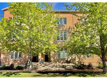 Inviting brick townhome featuring a well-maintained lawn and mature trees providing shade at 7525 E 1St Pl # 1010, Denver, CO 80230
