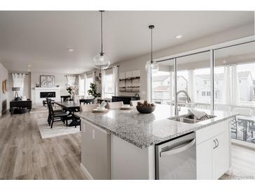 Open-concept kitchen boasts granite counters, stainless appliances, and seamless flow to dining and living areas at 7195 S Yantley Way, Aurora, CO 80016