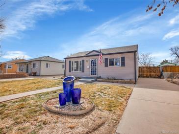 Charming single-story home boasts curb appeal with blue garden pots and American flag on a sunny day at 1681 Nome St, Aurora, CO 80010