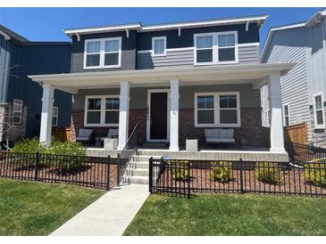 Charming two-story home with a welcoming front porch, lush lawn, and black iron fence at 10092 Flower St, Broomfield, CO 80021
