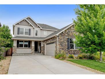 Beautiful two-story home with stone accents, manicured lawn, and a welcoming front porch at 8071 Tabor St, Arvada, CO 80005