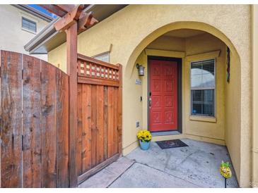 Inviting front entrance with a charming wooden gate and a vibrant red door under a sheltered archway at 9654 Martin Luther King Jr Blvd, Denver, CO 80238