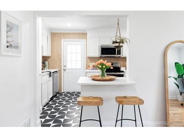 Bright kitchen with black and white tiled floor, white cabinets, and open breakfast bar area with stool seating at 2313 S Race St # A, Denver, CO 80210