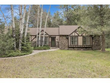Charming home featuring stone accents, Tudor-style detailing, and a well-maintained lawn, nestled amongst mature trees at 150 Soda Creek Rd, Evergreen, CO 80439
