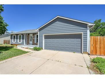 Charming single-story home featuring a two-car garage, and a well-maintained front yard under a clear blue sky at 19155 E Kansas Dr, Aurora, CO 80017