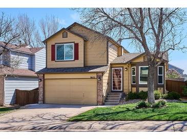 Two-story home with tan siding, brick accents, and a well-maintained lawn at 9652 Cove Creek Dr, Highlands Ranch, CO 80129