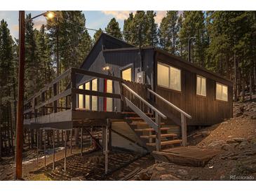 Charming home featuring a wooden porch and situated amongst a dense forest landscape at 153 Sawmill Ln, Idaho Springs, CO 80452