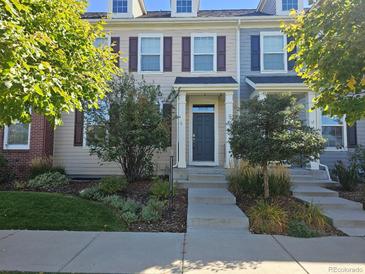 Tan two-story townhome with dark brown shutters and landscaping at 8436 E 35Th Ave, Denver, CO 80238