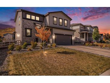 Two-story home with gray siding, stone accents, and a landscaped yard at 3455 Cade Ct, Castle Rock, CO 80104