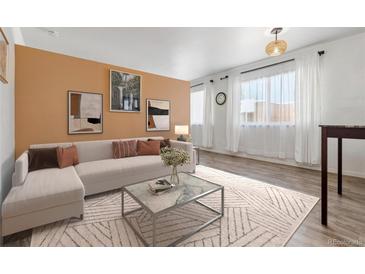 Bright living room with L-shaped sofa, coffee table, and wood-look floors at 855 N Pennsylvania St # 407, Denver, CO 80203