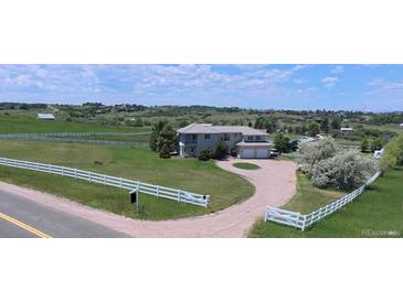 Stunning two-story home with white fencing, a circular driveway and manicured lawn at 595 W Oak Hill Ln, Castle Rock, CO 80108