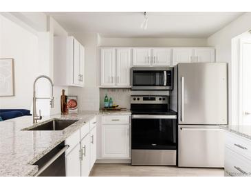 Bright kitchen featuring granite countertops, stainless steel appliances, and white cabinetry at 3026 W Prentice Ave # H, Littleton, CO 80123