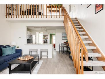 Bright living space features a loft, open staircase, and view into the updated kitchen at 3026 W Prentice Ave # H, Littleton, CO 80123