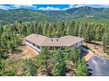 Stunning hillside home surrounded by evergreens featuring a wrap-around design and mountain views at 30671 Bearcat Trl, Conifer, CO 80433