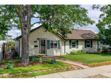 Charming home exterior with lush landscaping, lovely lawn, mature shade tree, and brick walkway to the front door at 334 S 7Th Ave, Brighton, CO 80601