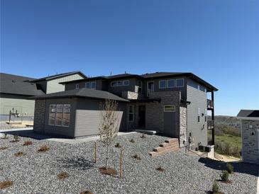 Modern two-story home featuring mixed stone and gray siding, set against a bright blue sky and minimal landscaping at 6036 Riesberg Ln, Castle Rock, CO 80104