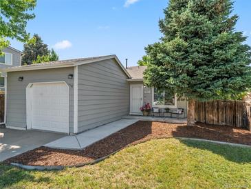 Charming home featuring a well-manicured lawn and an attached garage with a quaint outdoor seating area at 17411 E Layton Dr, Aurora, CO 80015