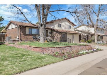 Charming two-story home with brick accents, landscaped yard, and mature trees under a beautiful blue sky at 4381 S Estes St, Littleton, CO 80123