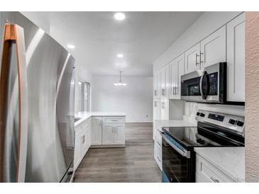 Kitchen with stainless appliances, modern countertops, and gray flooring next to dining area at 53 S Eagle Cir, Aurora, CO 80012