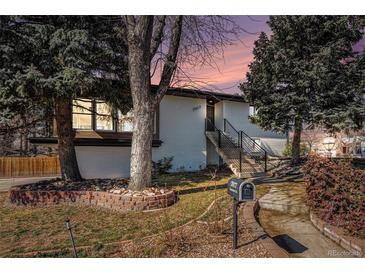 Charming single Gathering home with a brick facade, mature trees, and beautiful landscaping at 7077 Ammons St, Arvada, CO 80004