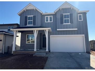 Charming two-story home with gray siding, white trim, a two-car garage, and a covered porch at 8836 Whiteclover St, Littleton, CO 80125