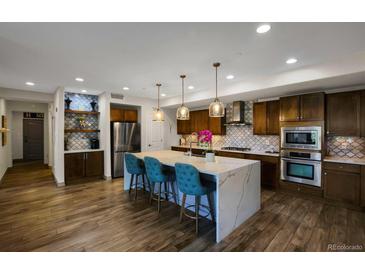 Modern kitchen featuring an island, stainless steel appliances, and stylish backsplash at 85 Rampart Way # 206, Denver, CO 80230